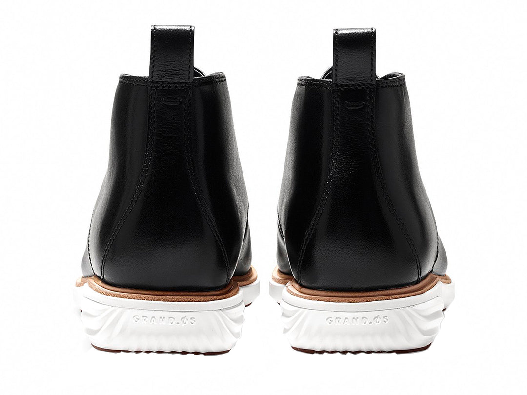 Par de botas chukka de cuero negro con suela blanca y cordones.