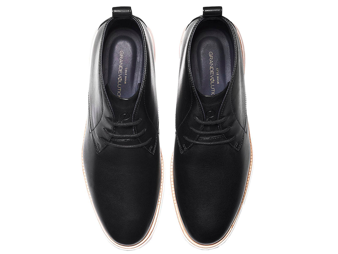 Par de botas chukka de cuero negro con suela blanca y cordones.