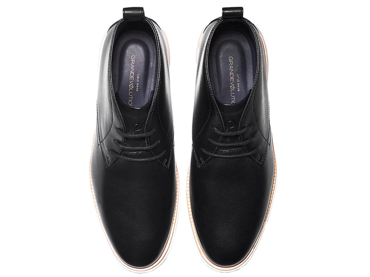 Par de botas chukka de cuero negro con suela blanca y cordones.