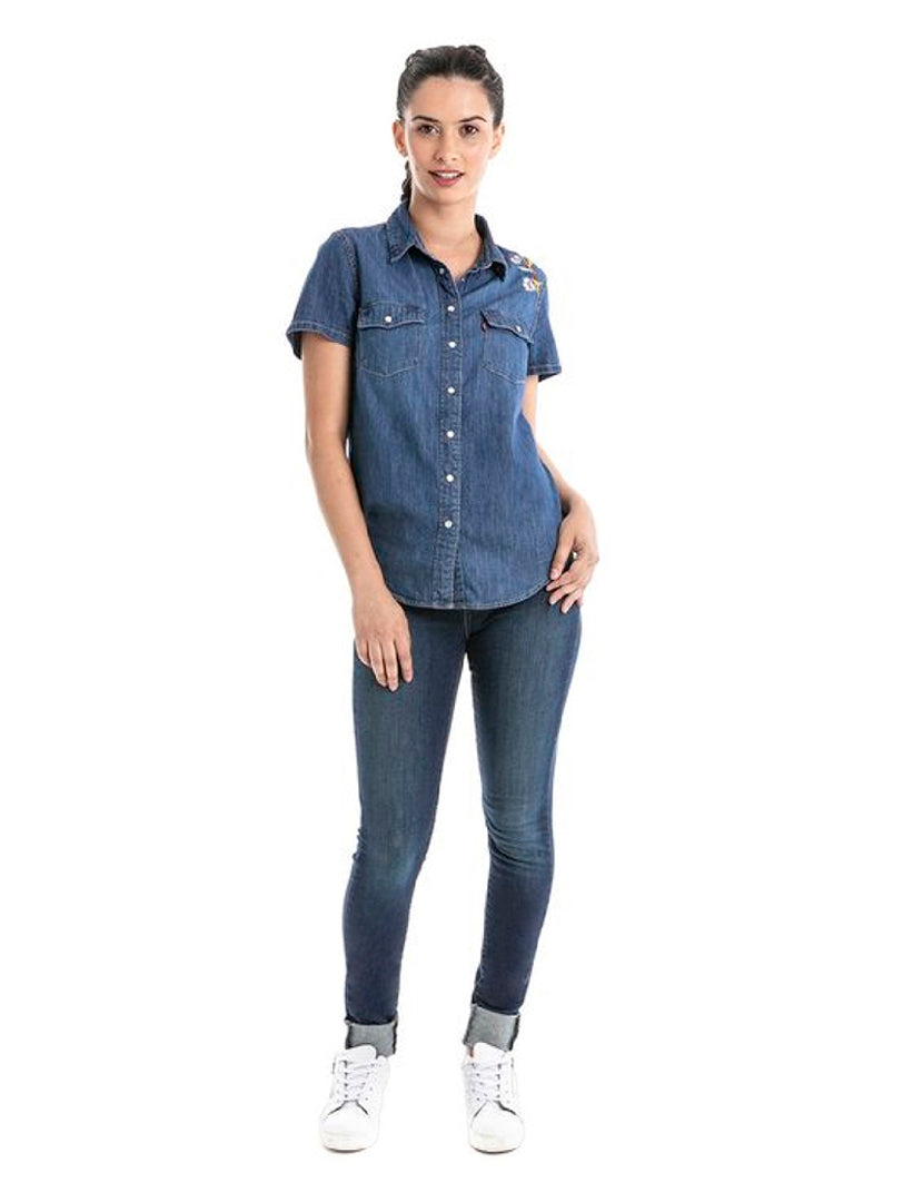 Mujer modelando jeans Levi's 710 Super Skinny color indigo ridge con camisa de mezclilla y tenis blancos.