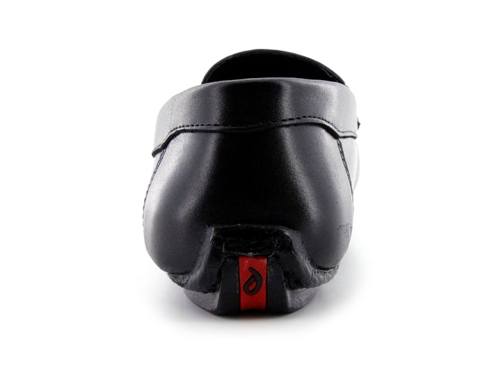 Zapato tipo mocasín de cuero negro con detalle de hebilla metálica y suela roja.