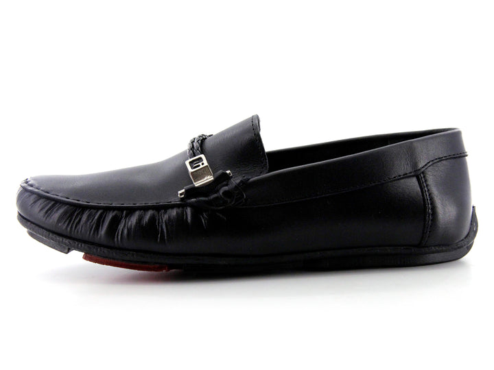 Zapato tipo mocasín de cuero negro con detalle de hebilla metálica y suela roja.