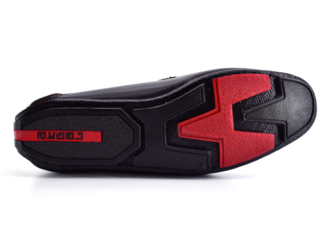 Zapato tipo mocasín de cuero color negro con detalle rojo en la suela, vista lateral.