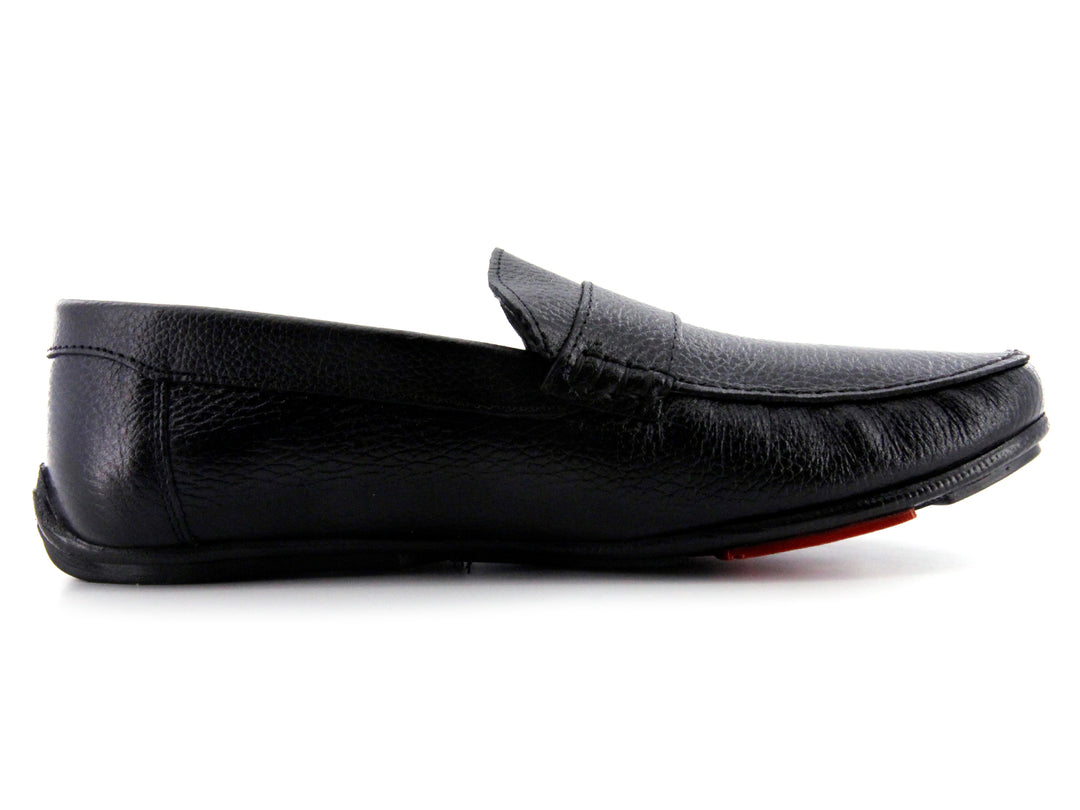 Zapato tipo mocasín de cuero negro con textura rugosa y detalle en la suela color rojo.