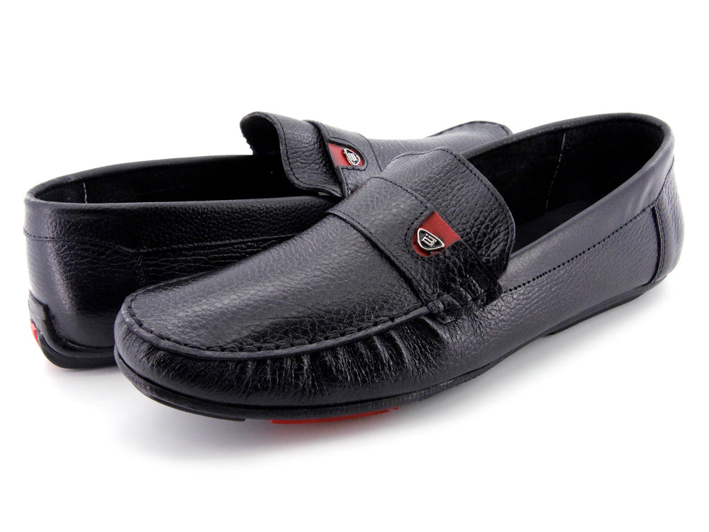 Zapato tipo mocasín de cuero negro con textura rugosa y detalle en la suela color rojo.