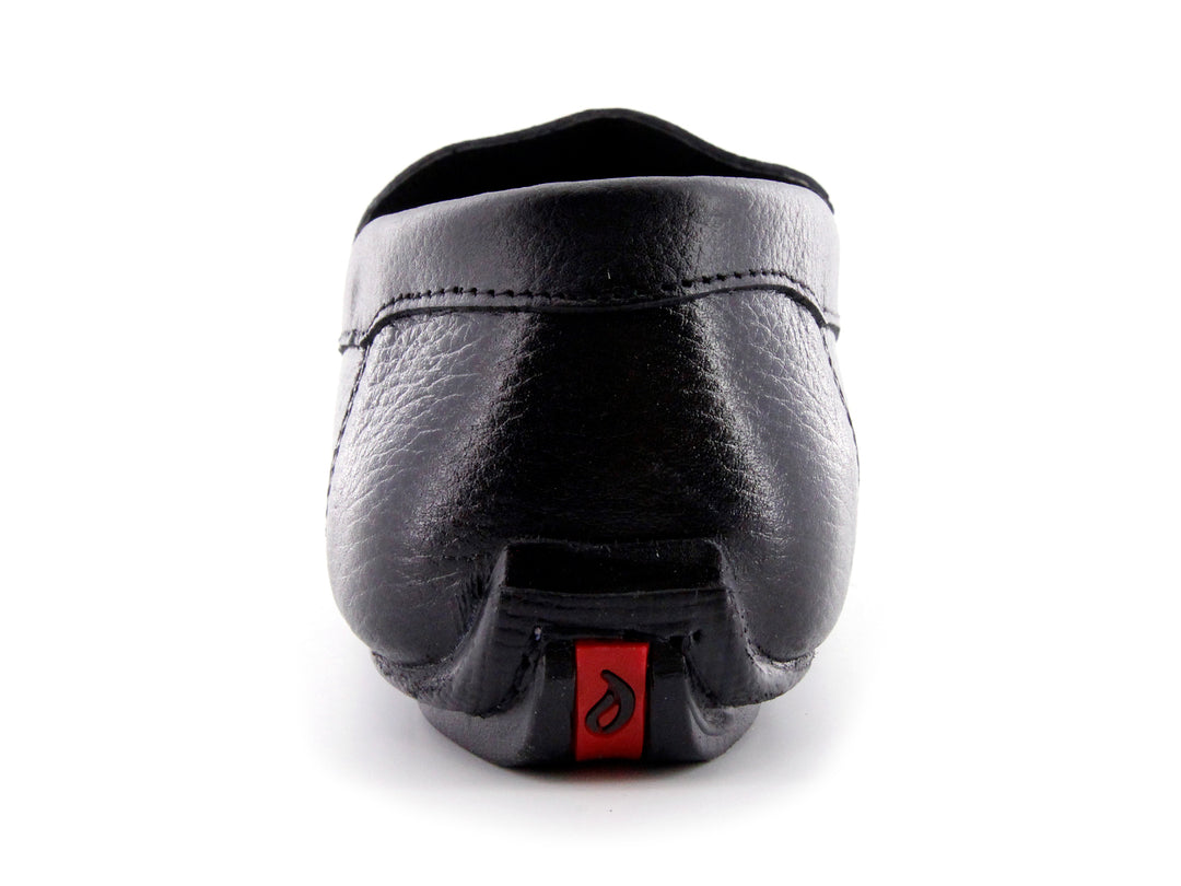 Zapato tipo mocasín de cuero negro con textura rugosa y detalle en la suela color rojo.