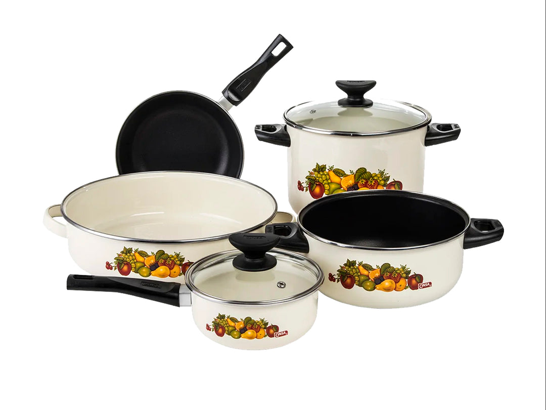 Batería de cocina blanca de 7 piezas con detalles de vegetales y mangos negros.