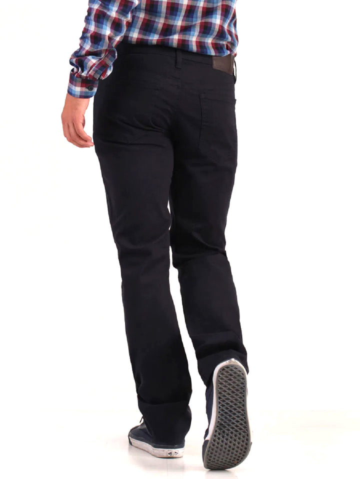 Hombre vistiendo pantalones jeans color marino de corte casual y calzado deportivo.