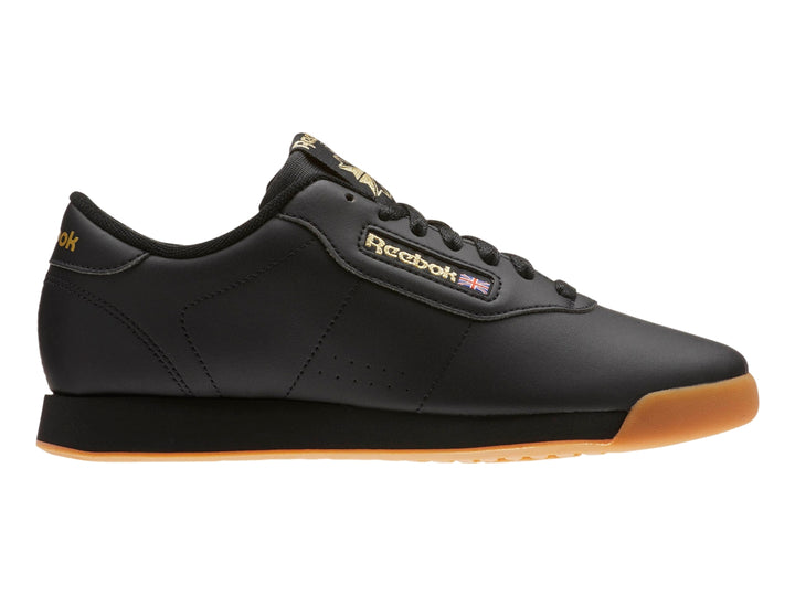 Tenis Reebok color negro con suela color miel y detalles dorados en el logotipo.