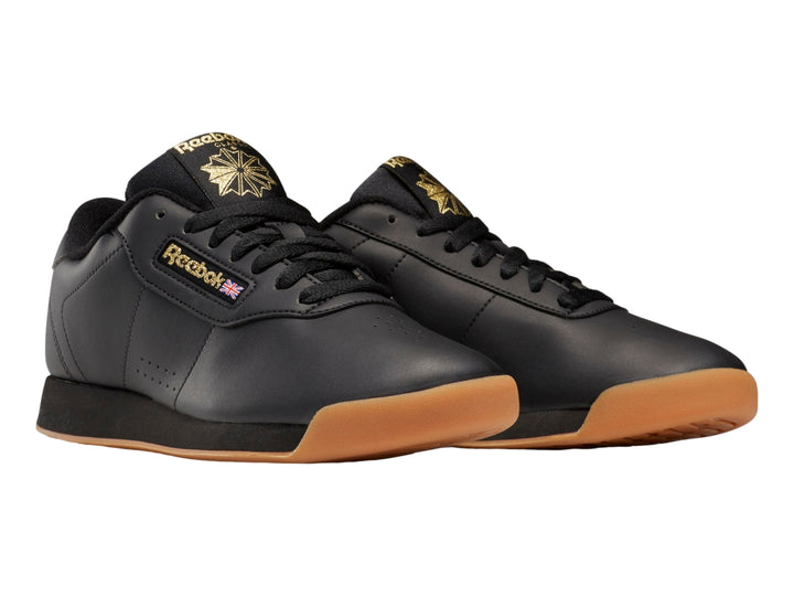 Tenis Reebok color negro con suela color miel y detalles dorados en el logotipo.