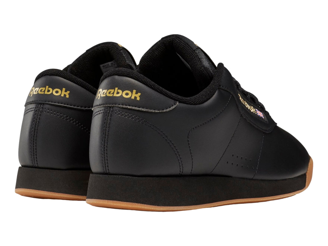 Tenis Reebok color negro con suela color miel y detalles dorados en el logotipo.