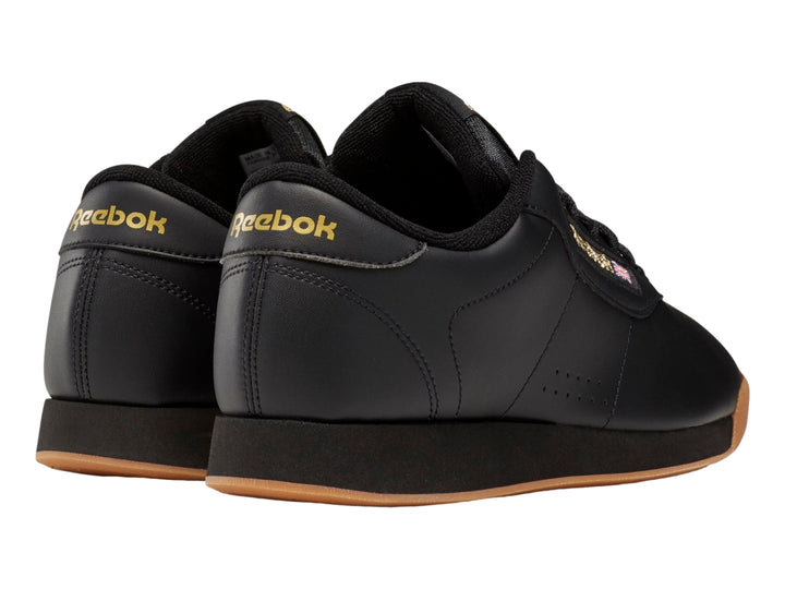 Tenis Reebok color negro con suela color miel y detalles dorados en el logotipo.
