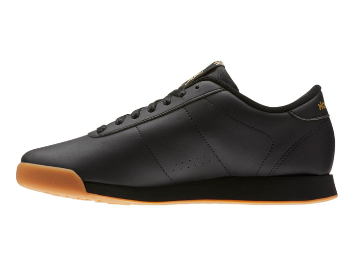 Tenis Reebok color negro con suela color miel y detalles dorados en el logotipo.