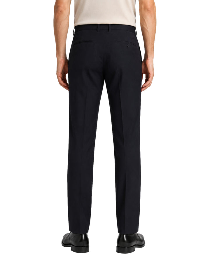 Hombre vistiendo un pantalón formal de color negro, corte recto y zapatos negros.