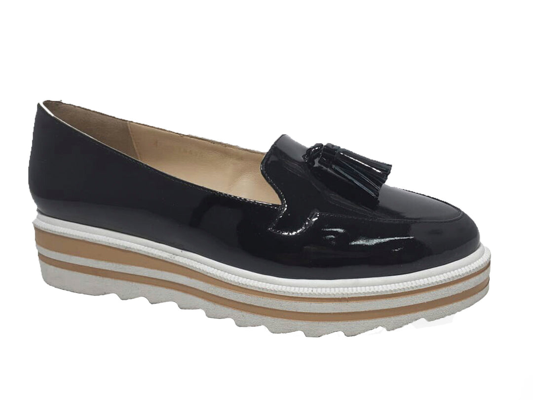 Mocasines negros de charol con borla y suela plataforma en colores blanco y beige.