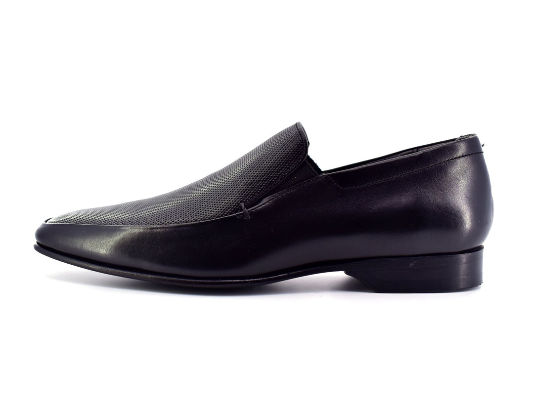 Zapato slip-on color negro para hombre con detalle perforado en la parte superior.