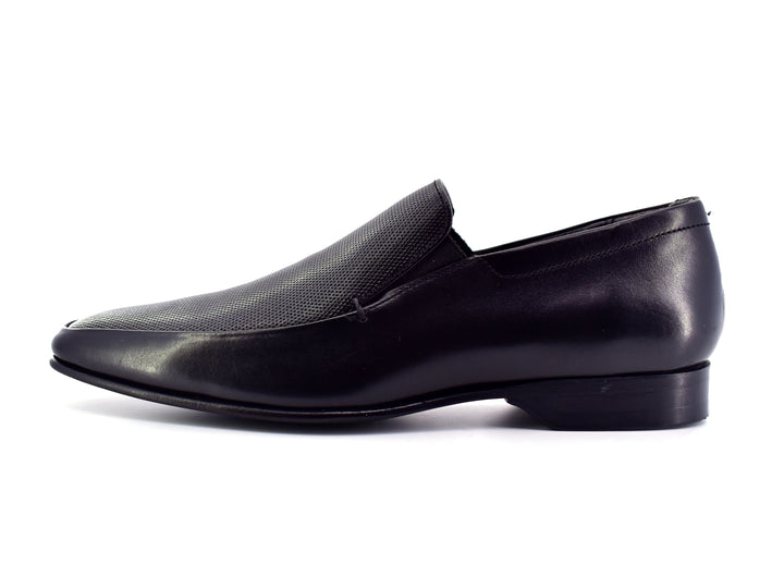 Zapato slip-on color negro para hombre con detalle perforado en la parte superior.