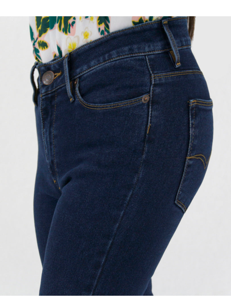 Mujer vistiendo jeans ajustados color azul oscuro con tacones beige sobre fondo blanco.