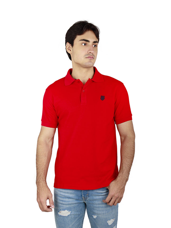 Hombre vistiendo una playera polo de color rojo marca K-Swiss y pantalones mezclilla azules.