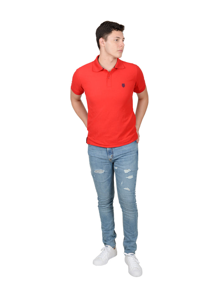 Hombre vistiendo una playera polo de color rojo marca K-Swiss y pantalones mezclilla azules.