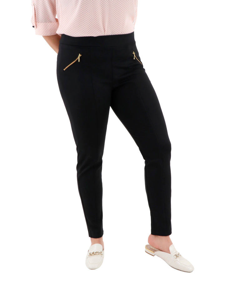 Mujer vistiendo leggings negros ajustados con detalles de cremalleras doradas en los bolsillos.