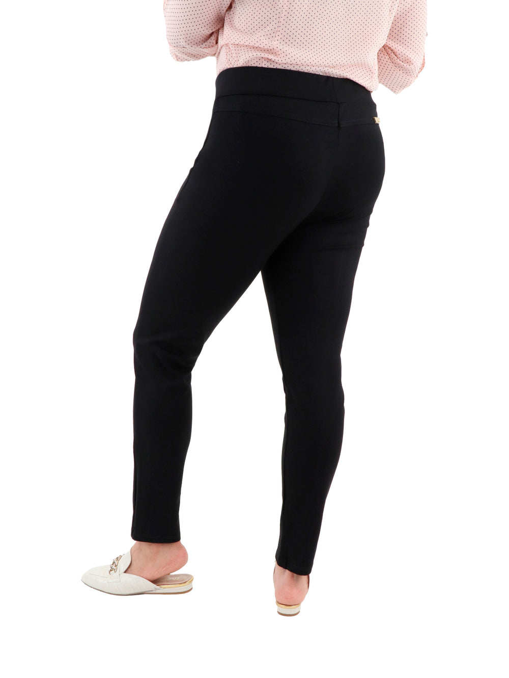 Mujer vistiendo leggings negros ajustados con detalles de cremalleras doradas en los bolsillos.