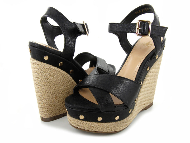 Sandalias negras de plataforma con cuña de yute y remaches dorados.