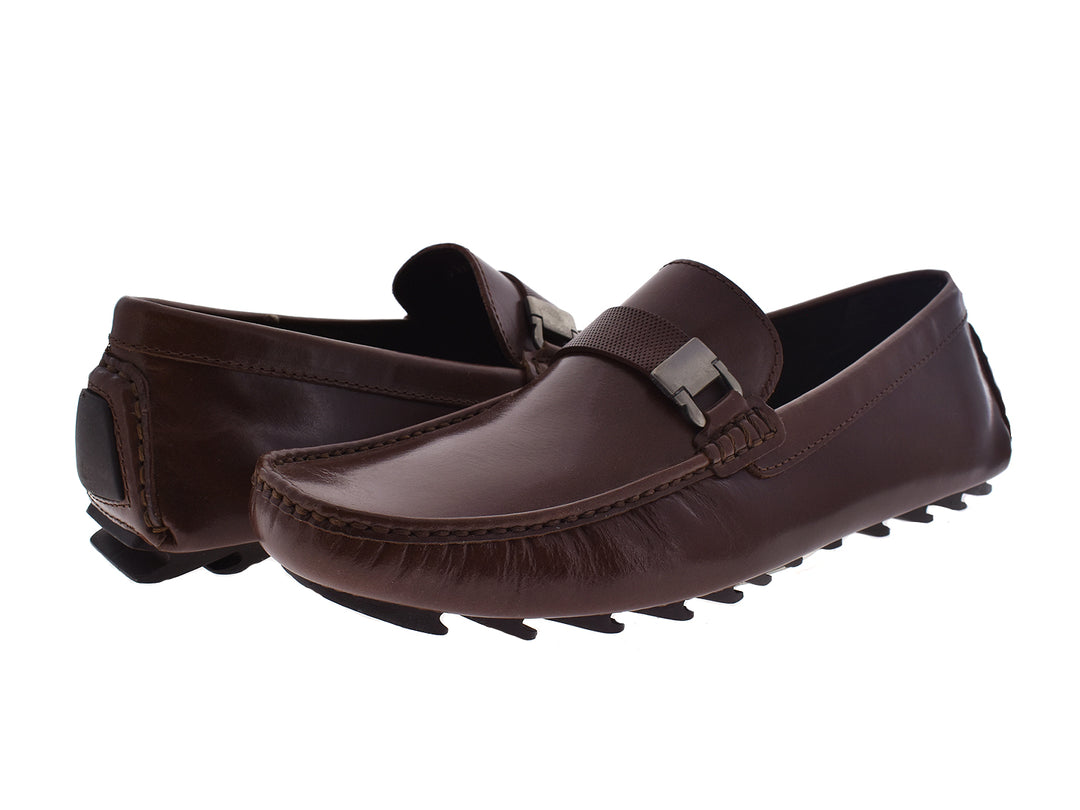 Zapatos mocasines de cuero color caoba para hombre con detalle de hebilla metálica.