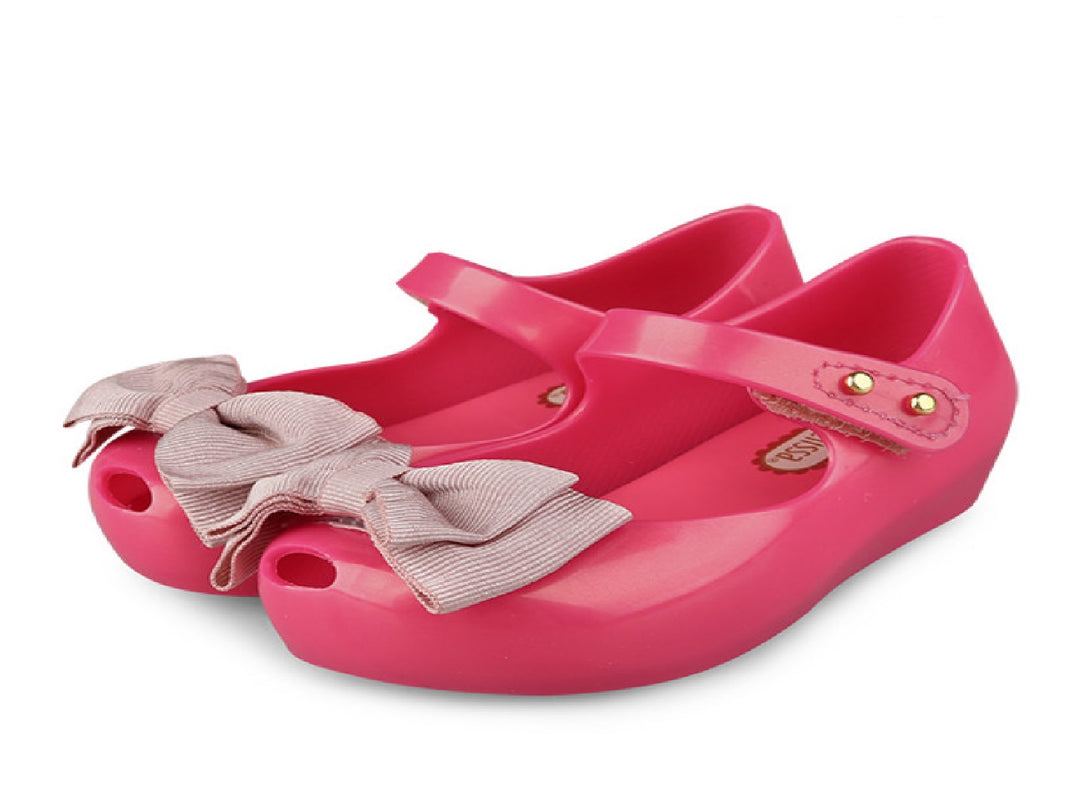 Sandalias infantiles Mini Melissa color rosa oscuro con moño decorativo en la parte frontal.