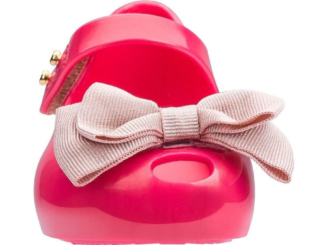 Sandalias infantiles Mini Melissa color rosa oscuro con moño decorativo en la parte frontal.