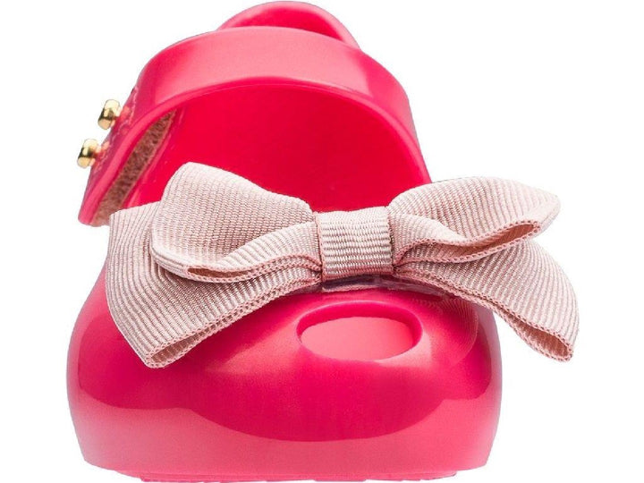 Sandalias infantiles Mini Melissa color rosa oscuro con moño decorativo en la parte frontal.