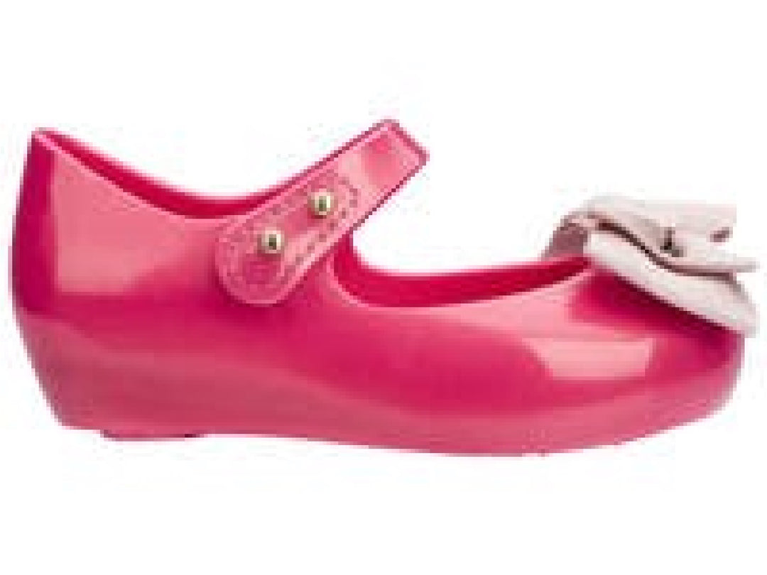 Sandalias infantiles Mini Melissa color rosa oscuro con moño decorativo en la parte frontal.