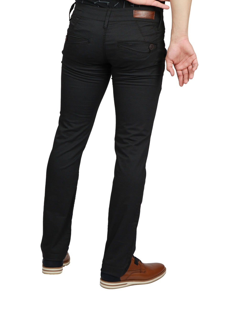 Hombre vistiendo pantalón de gabardina color negro y zapatos color marrón sobre fondo blanco.