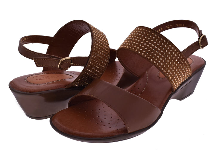 Sandalias color miel para mujer con tacón cuña y correas decoradas con tachuelas doradas.