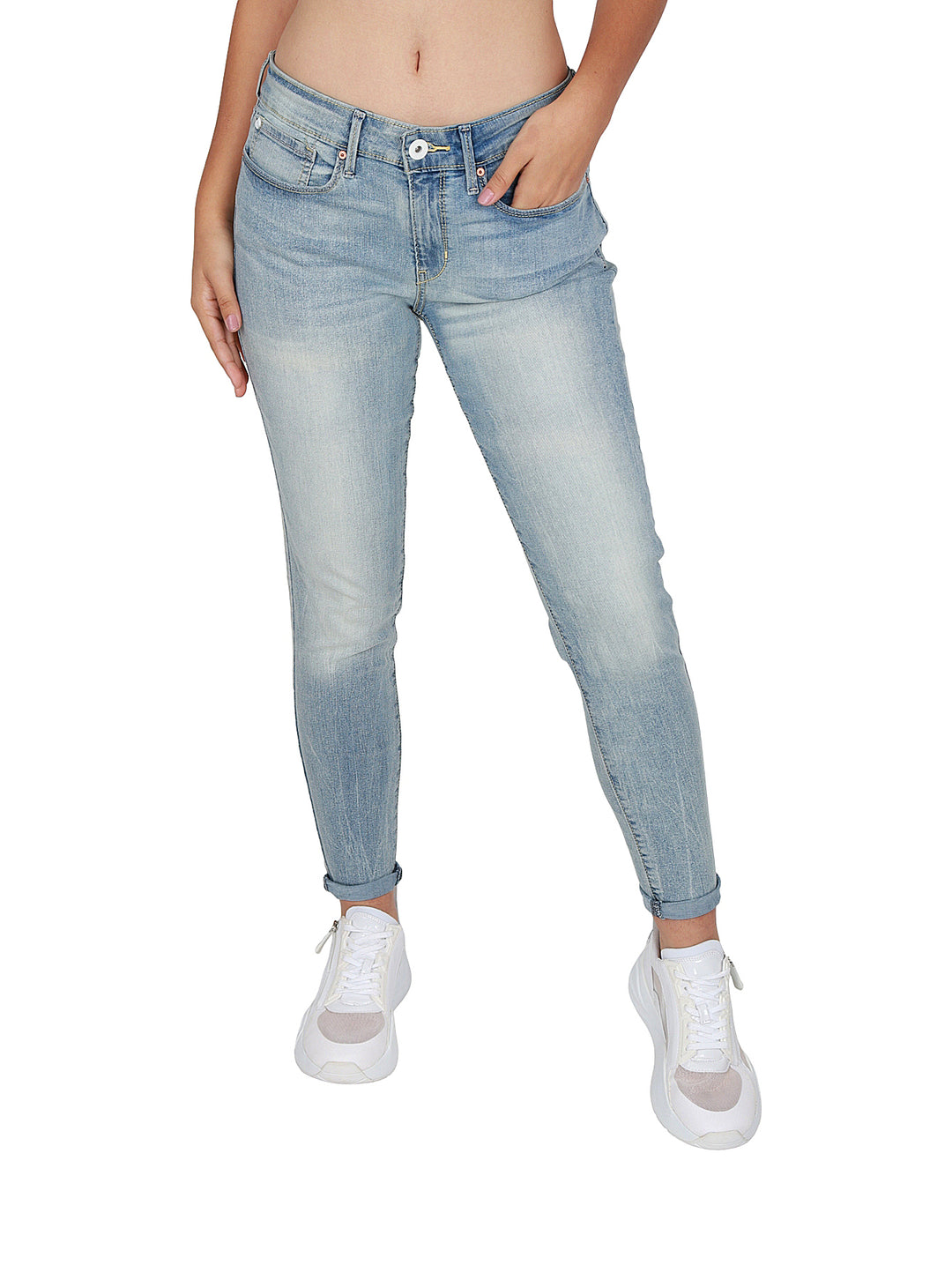 Mujer vistiendo pantalones jeans ajustados de color azul claro deslavado y tenis blancos.