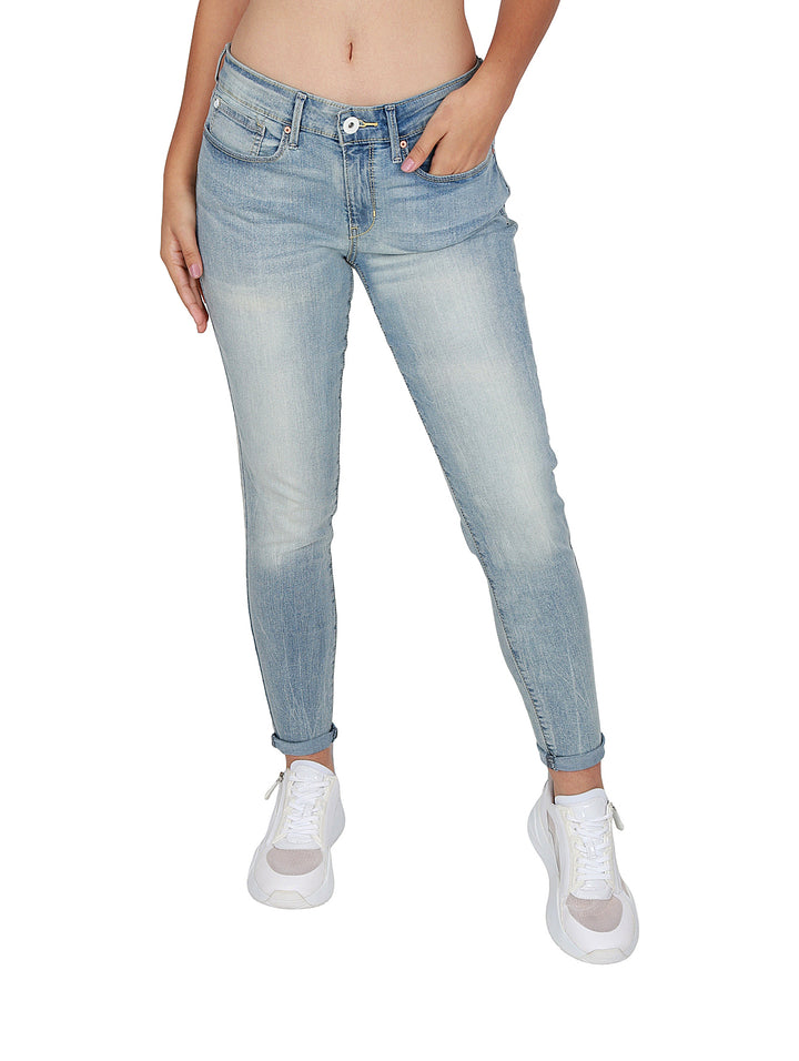 Mujer vistiendo pantalones jeans ajustados de color azul claro deslavado y tenis blancos.