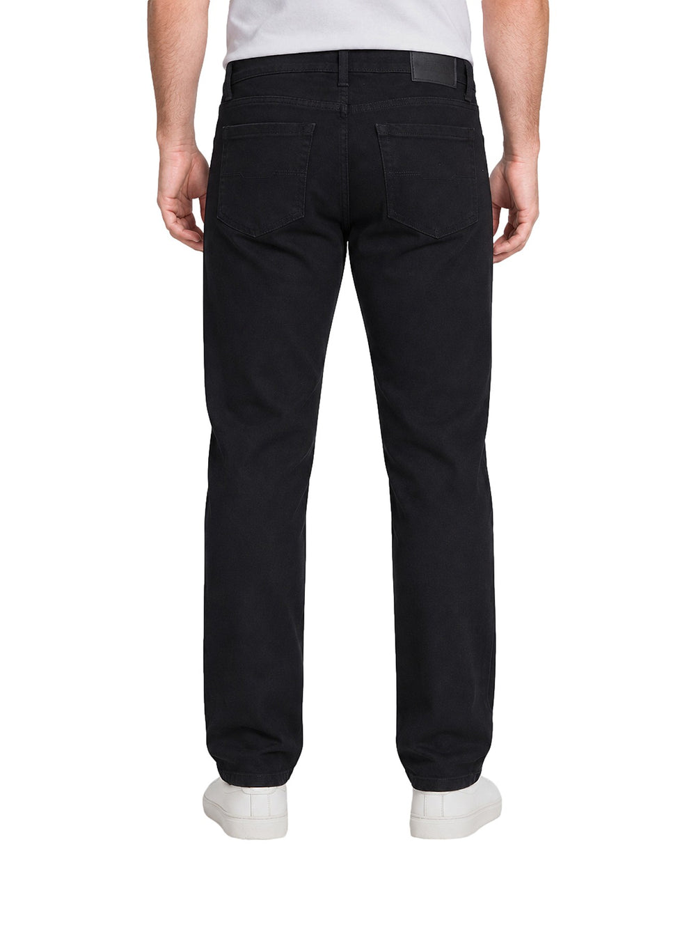Hombre vistiendo jeans plus size de color negro, corte recto, combinados con camiseta blanca y tenis blancos.
