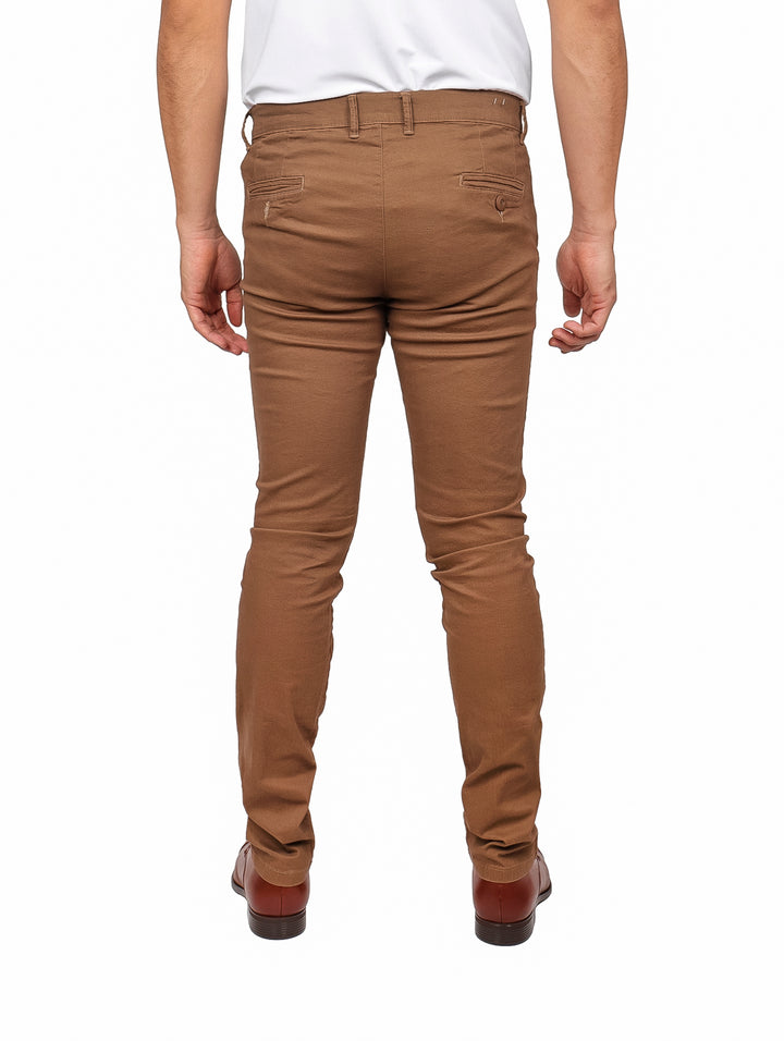 Hombre vistiendo pantalón de gabardina color khaki de corte ajustado y zapatos cafés.