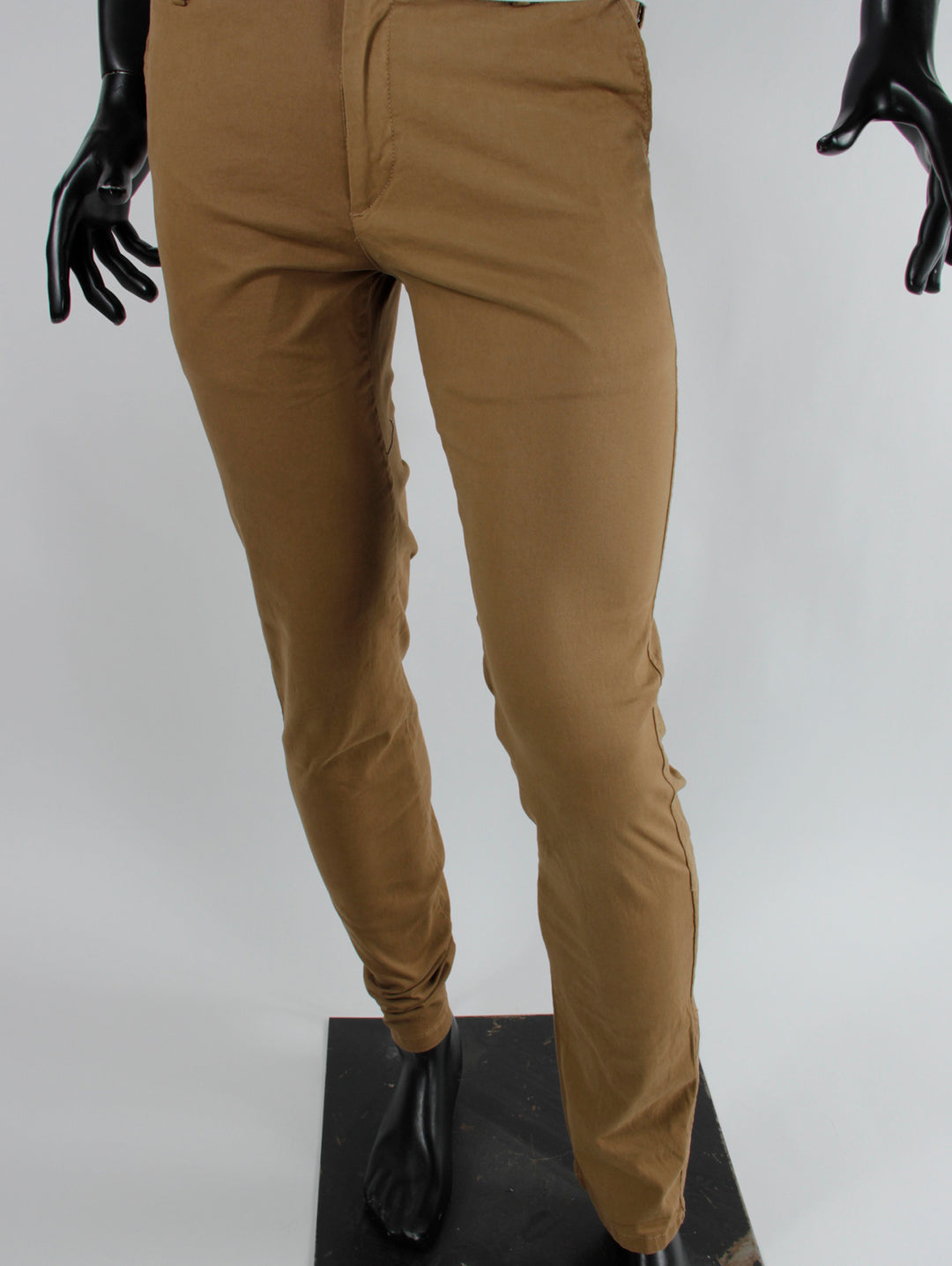 Pantalón color beige de corte slim fit para hombre exhibido en maniquí negro.