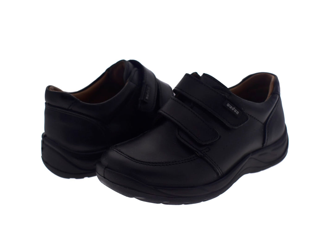 Par de zapatos negros para niño con cierre de velcro.
