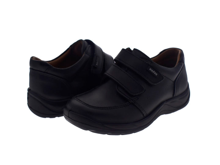 Par de zapatos negros para niño con cierre de velcro.