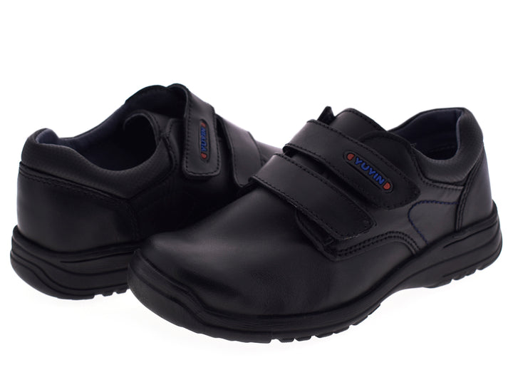 Par de zapatos negros para niño con cierre de velcro y suela gruesa.
