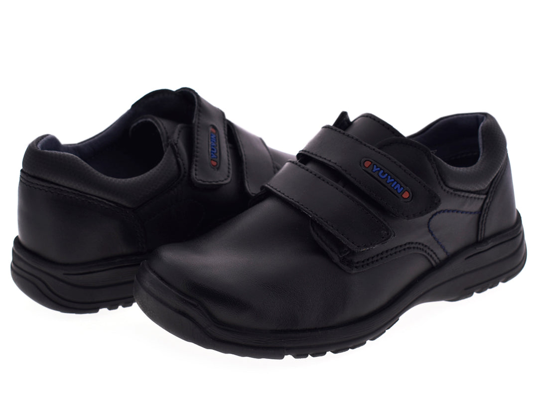 Par de zapatos negros para niño con cierre de velcro y suela gruesa.