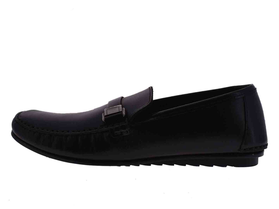 Par de mocasines negros para niño con detalle de hebilla metálica en la parte superior.