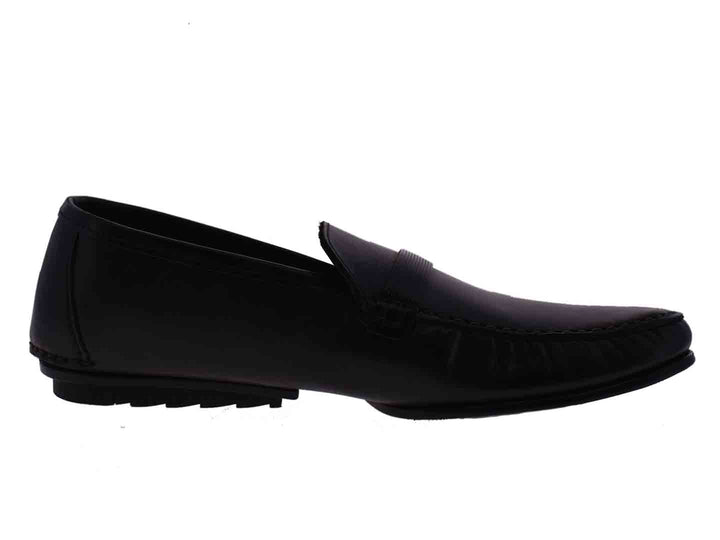 Par de mocasines negros para niño con detalle de hebilla metálica en la parte superior.