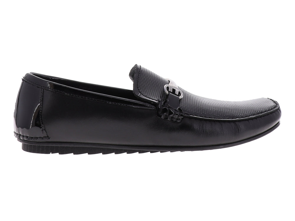 Zapato tipo mocasín Gino Cherruti en color negro con acabado de charol y detalle metálico superior.