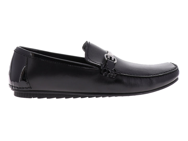 Zapato tipo mocasín Gino Cherruti en color negro con acabado de charol y detalle metálico superior.