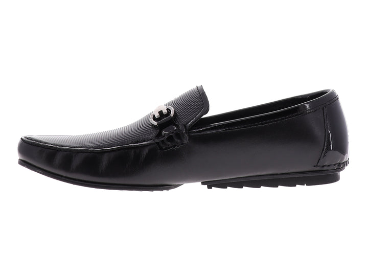 Zapato tipo mocasín Gino Cherruti en color negro con acabado de charol y detalle metálico superior.