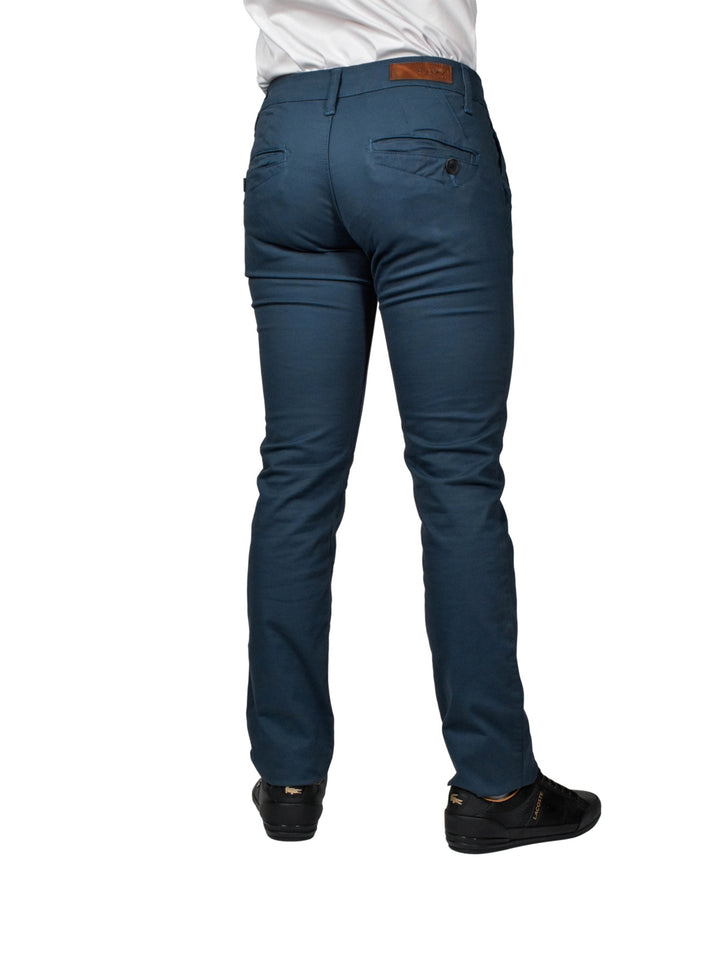 Hombre vistiendo pantalón de gabardina color azul babel, zapatos negros y camisa blanca.