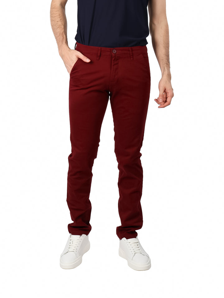 Hombre vistiendo pantalón de gabardina color vino con corte ajustado y tenis blancos.